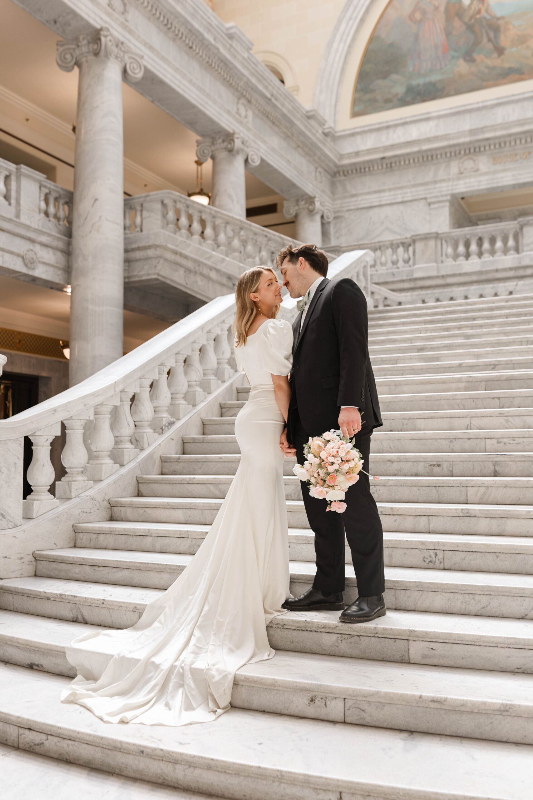 Candid shot of a bride and groom mid-conversation on grand marble stairs, perfectly captured by a travel elopement photographer.