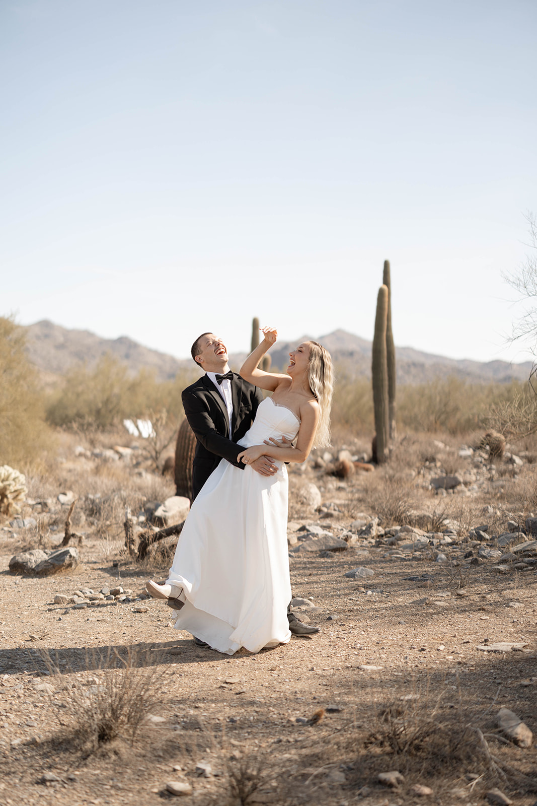 Bride and groom laughing mid-spin in the golden light of one of the most iconic Arizona elopement locations.