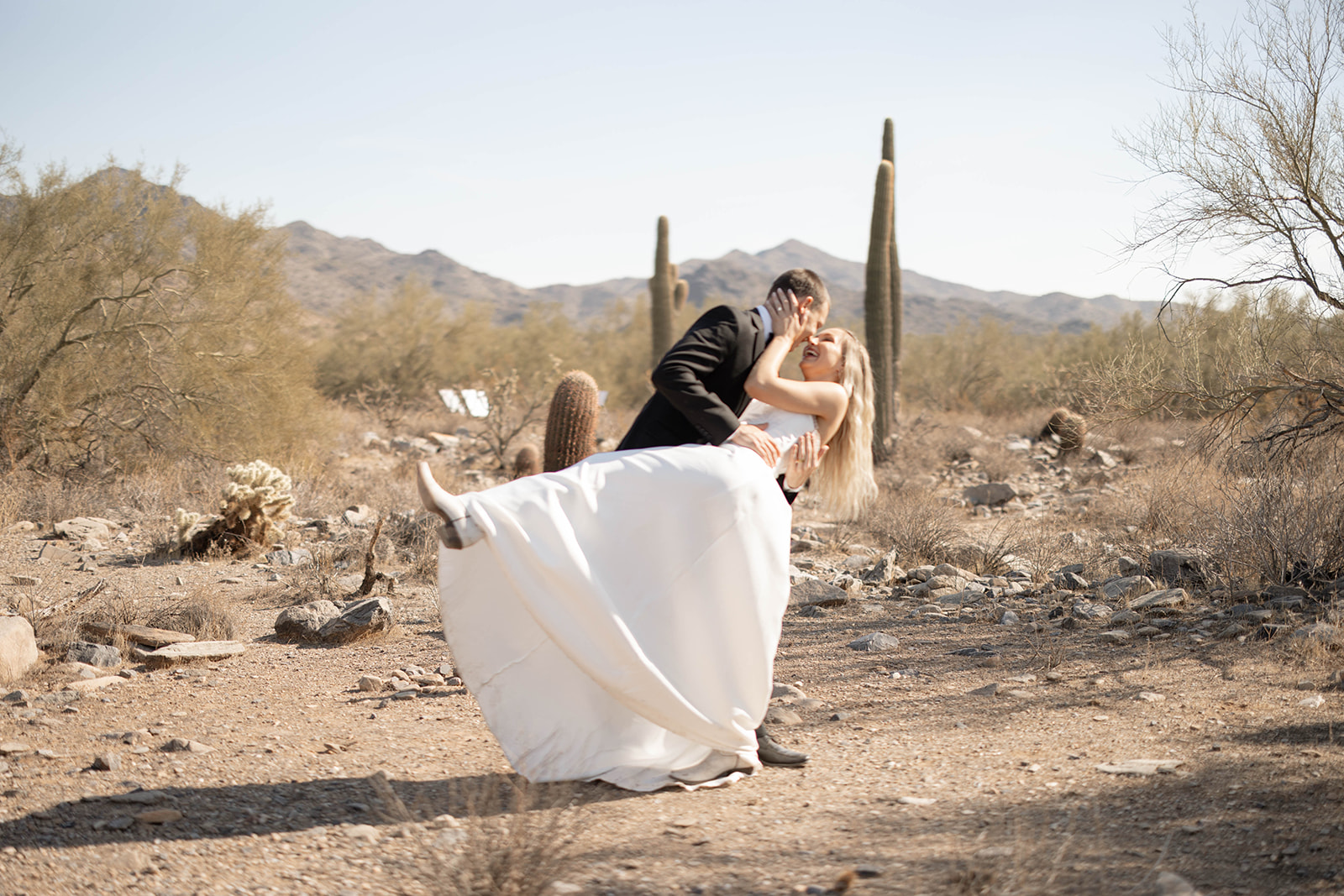 A playful and romantic kiss among cacti and desert scenery at one of the best Arizona elopement locations.