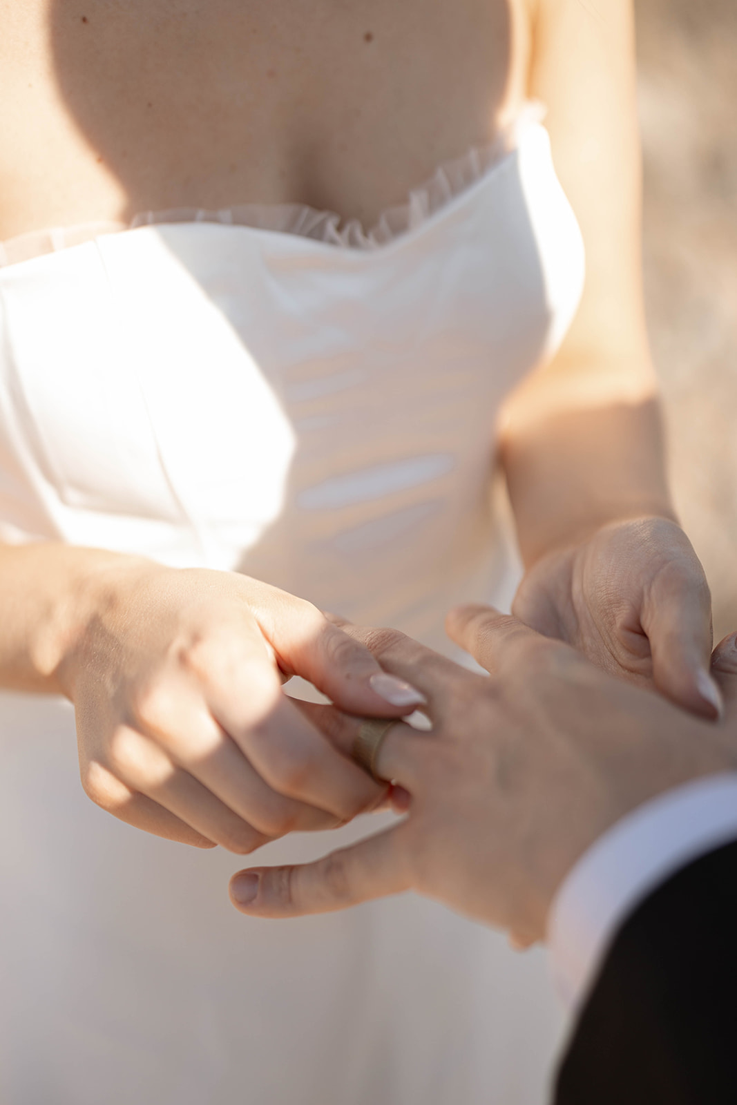 Bride slipping a wedding ring onto the groom’s finger during their intimate ceremony in the desert.