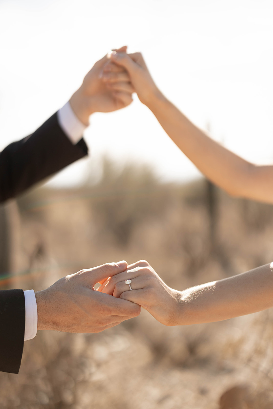A detail shot of the couple’s hands intertwined, the bride’s engagement ring sparkling in the Arizona sun.