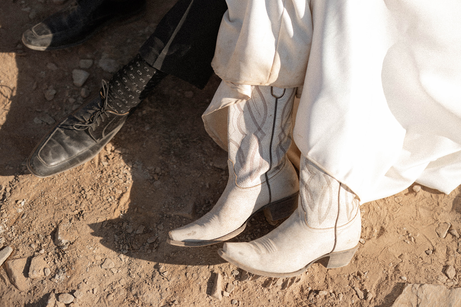 Western-inspired detail shot of the bride’s white cowboy boots beside the groom’s dress shoes—perfectly capturing the vibe of Arizona elopement locations.