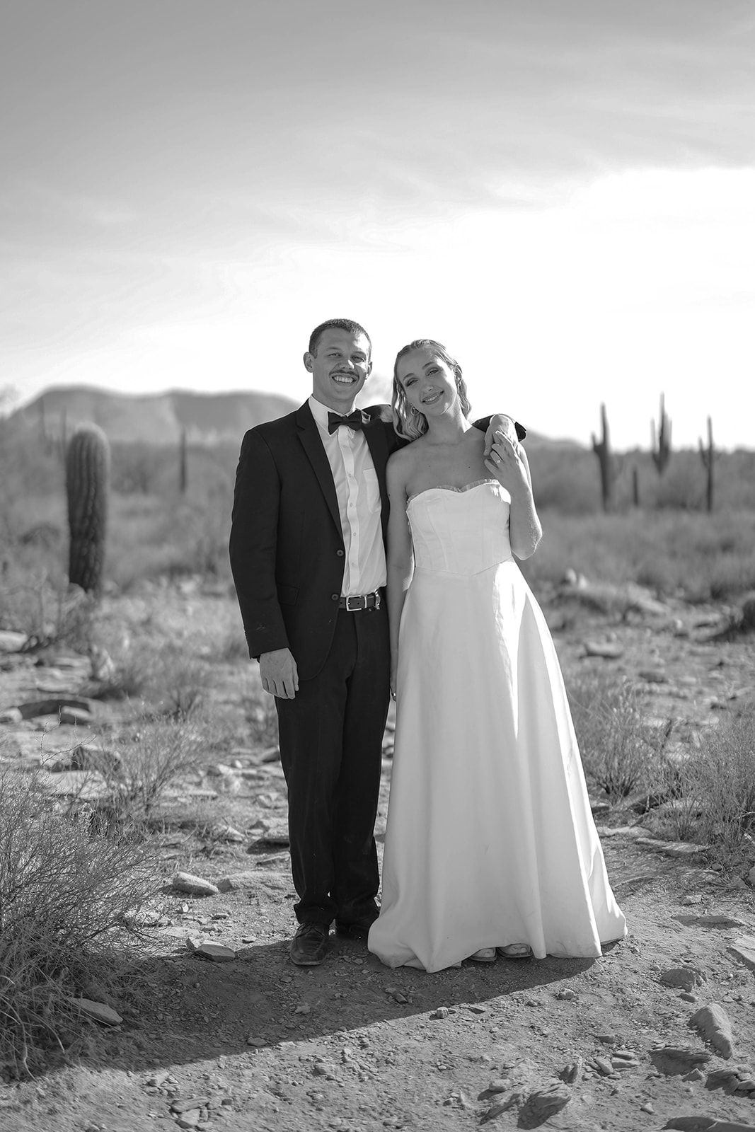 Bride and groom smiling together in one of the best Arizona elopement locations with saguaros and mountains behind them.