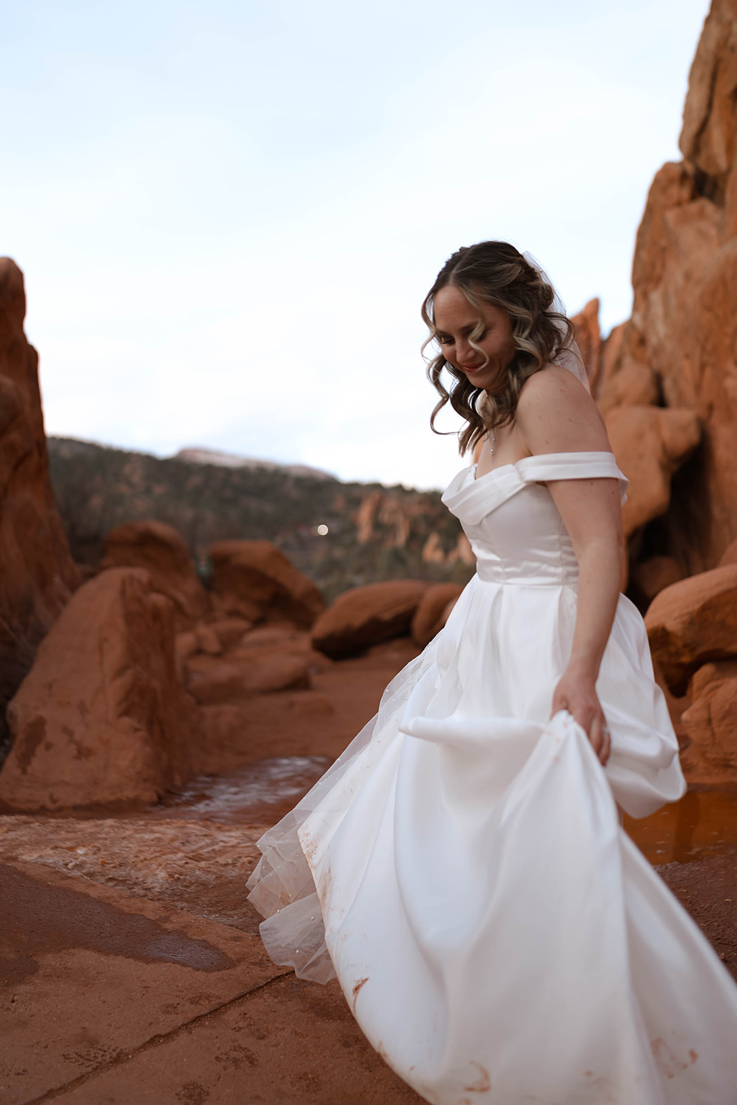The bride walks through the red rock formations in her wedding gown, soaking in the peacefulness of her elopement day.