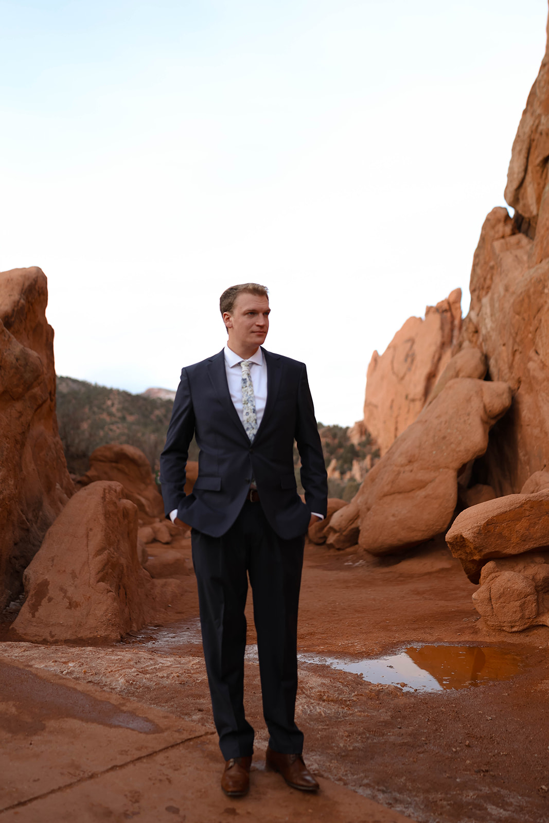 The groom stands confidently among the red rocks, waiting for his bride during their intimate Colorado elopement.