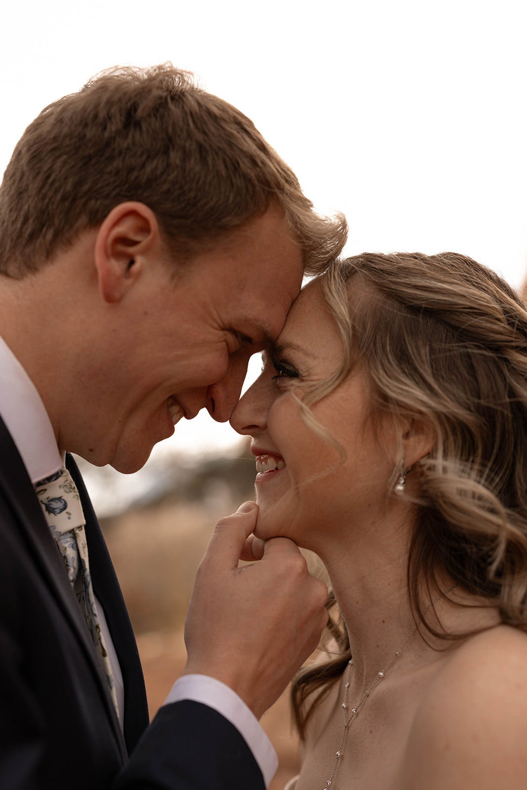 A joyful close-up of a couple smiling and pressing their foreheads together, capturing a sweet, candid elopement moment.