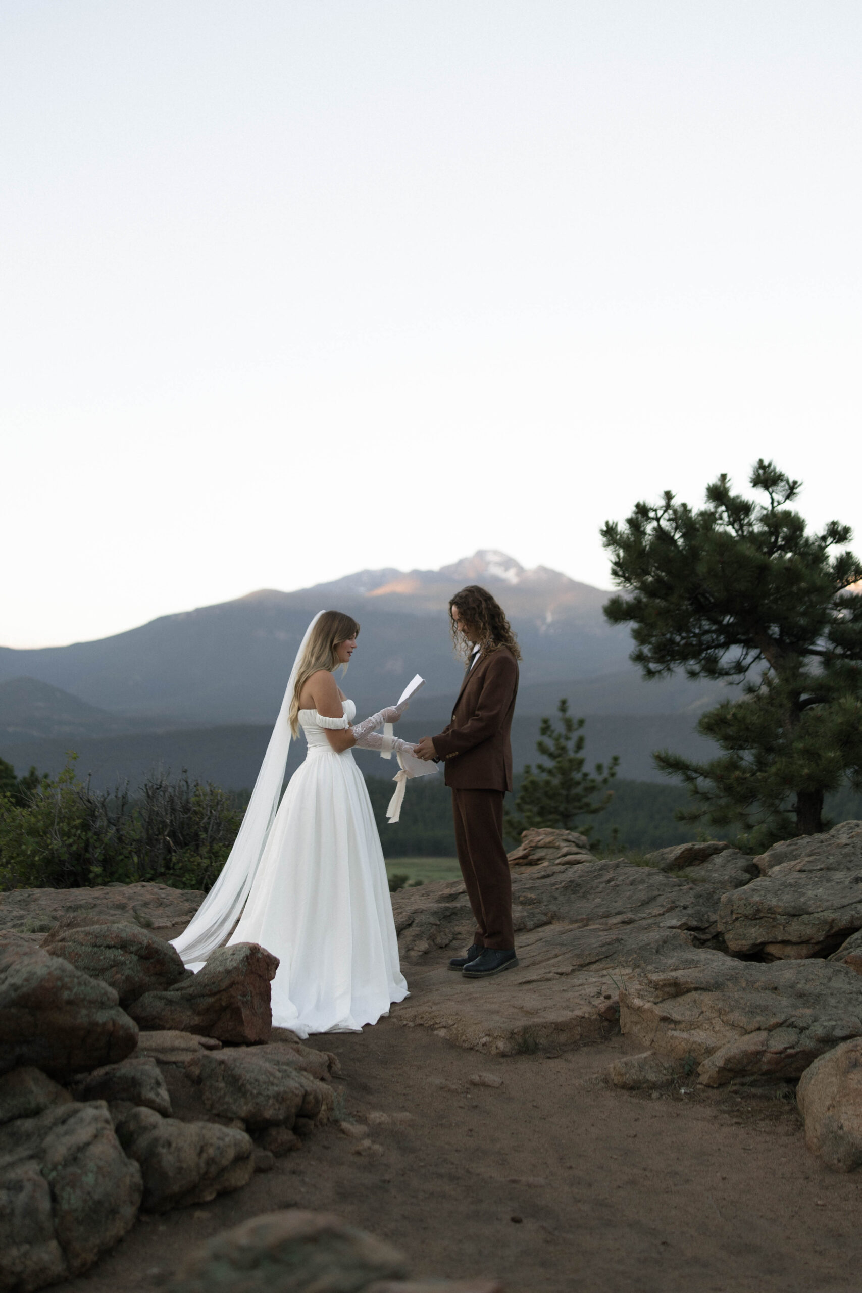 The couple exchanges vows atop a rocky overlook, with towering peaks in the background—an intimate ceremony at one of the most iconic Colorado elopement locations.