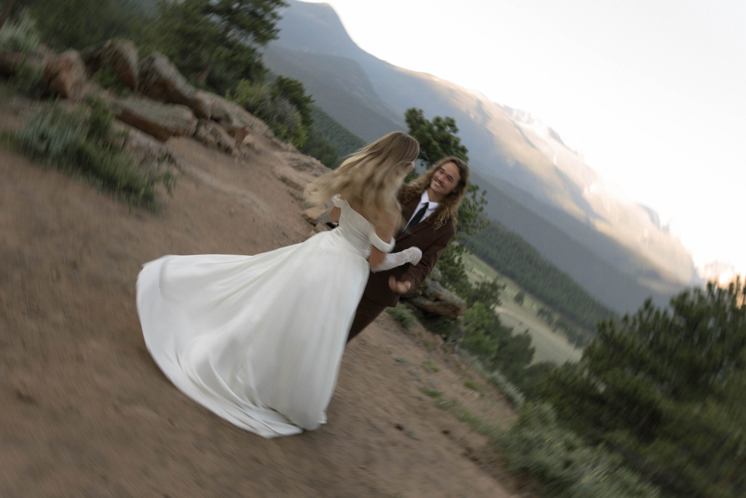 A playful moment as the bride twirls in her gown, surrounded by forested peaks and fresh mountain air, showcasing the joyful spirit of Colorado elopement locations.