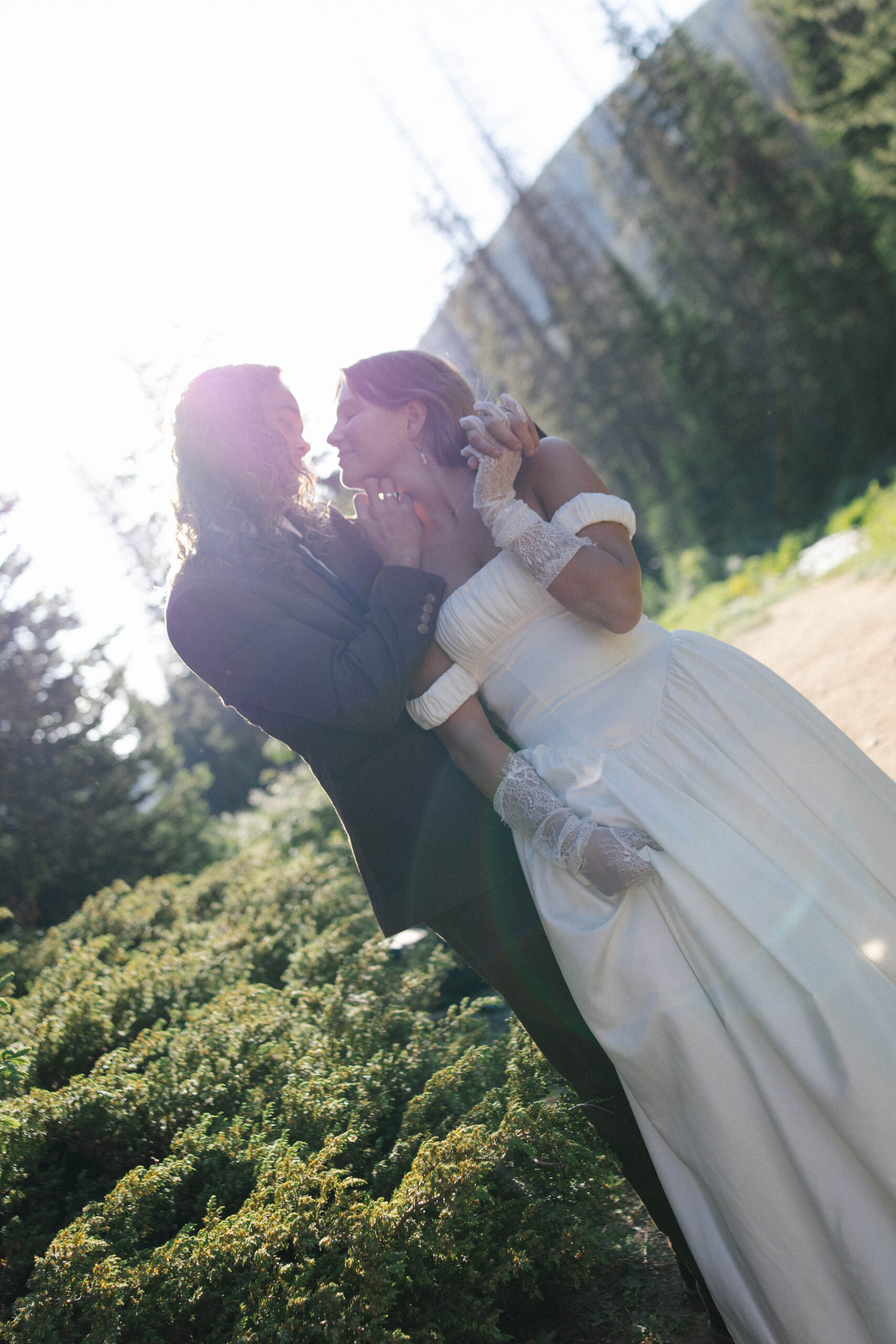 A romantic, backlit moment as a bride and groom gaze into each other’s eyes, the sunlight casting a dreamy glow during their mountain elopement in one of the most scenic Colorado elopement locations.