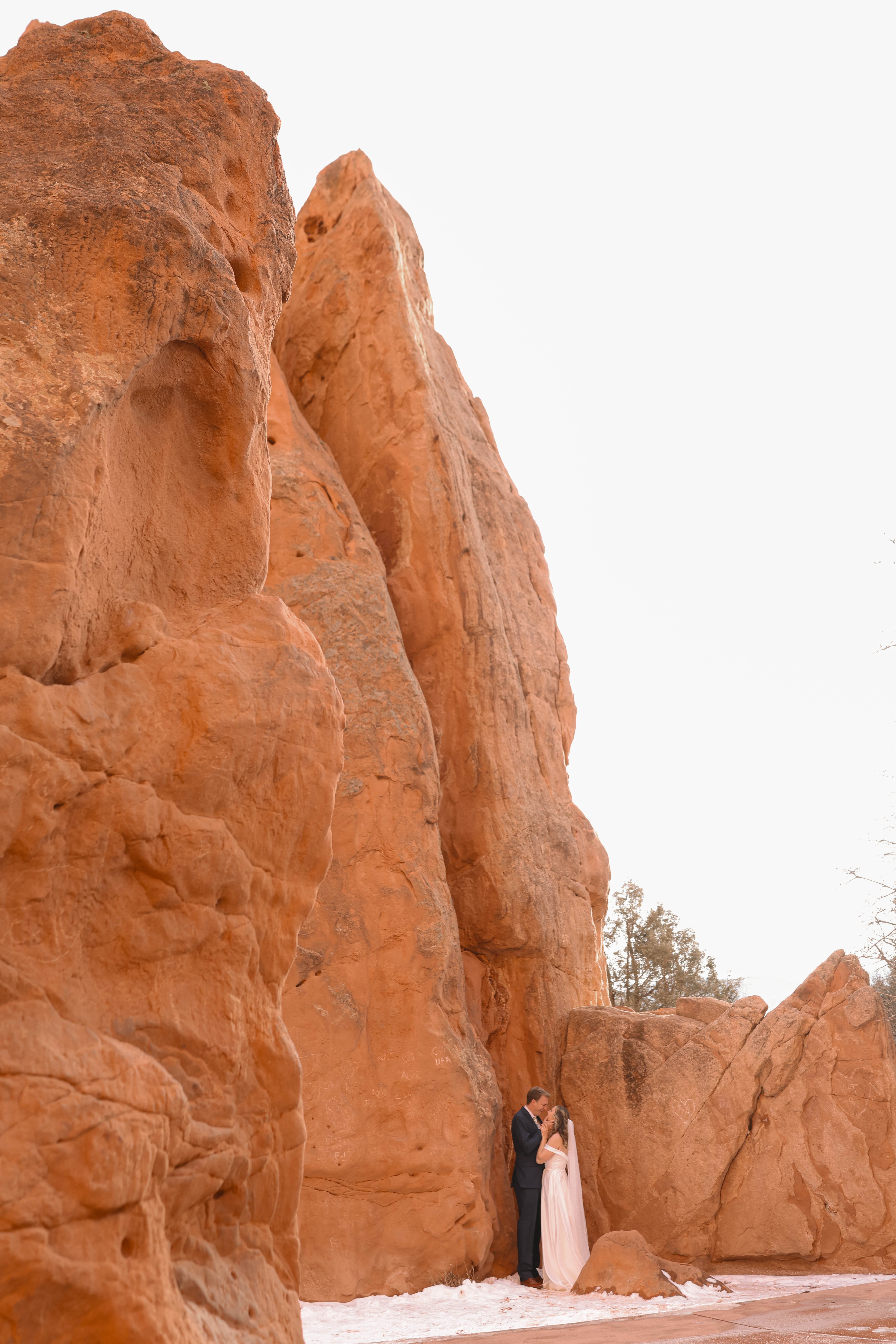A bride and groom stand together in awe of the towering red sandstone formations, highlighting the grandeur of their elopement location.