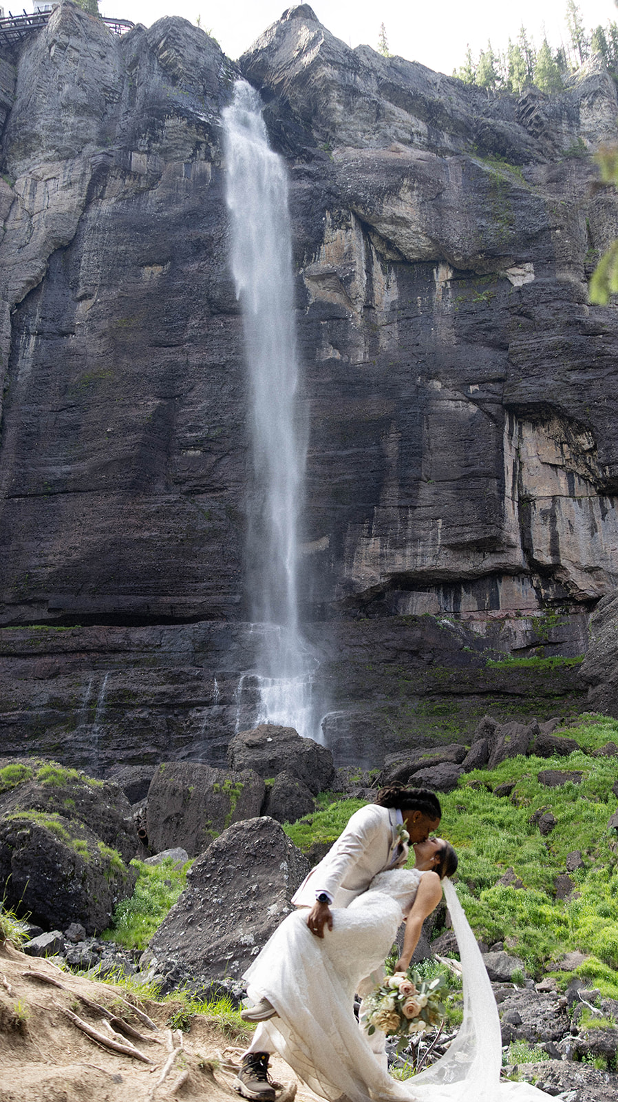 Groom dips bride for a kiss with sweeping alpine views behind them during their Telluride elopement.