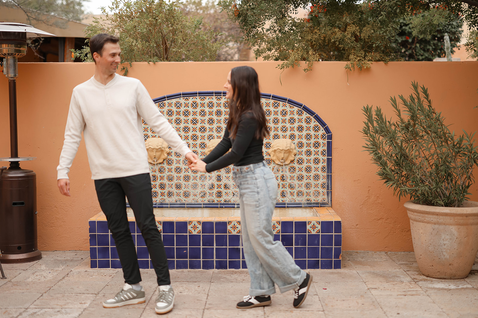 Colorful couples photos with the couple smiling at each other in front of a blue-tiled fountain wall.