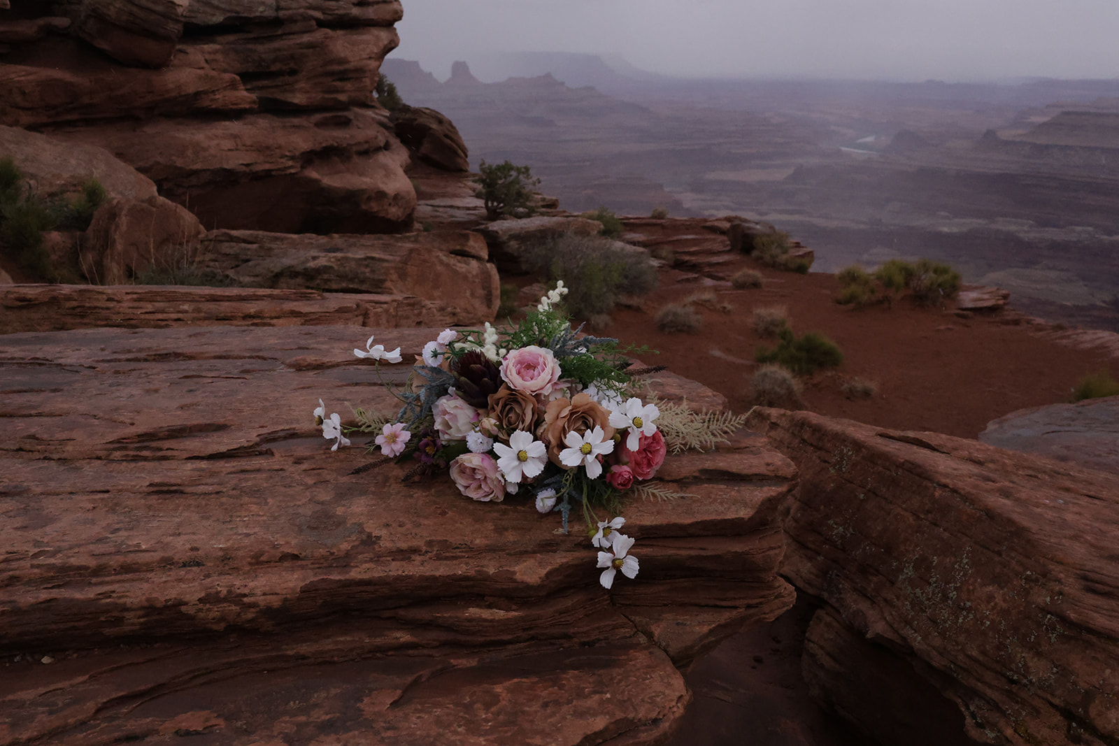 Textured desert bouquet with wildflowers and roses arranged on sandstone during an intimate elopement.