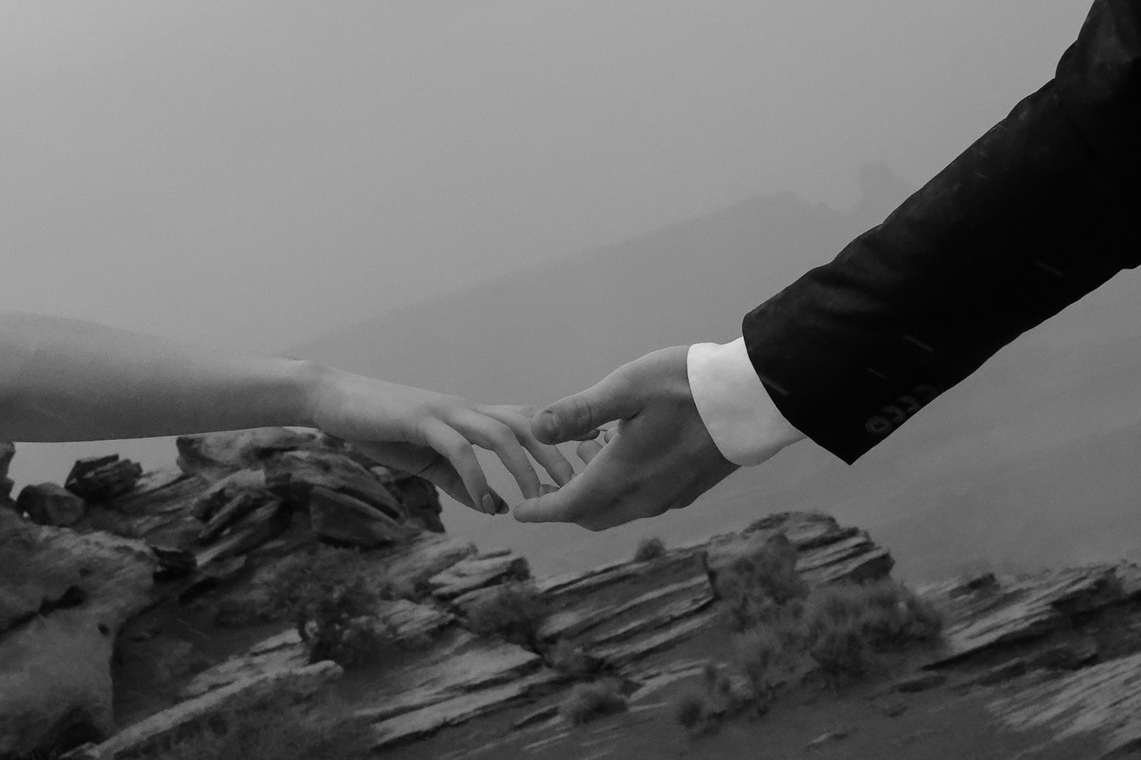 Artistic black and white detail of two hands reaching toward one another during a desert elopement.