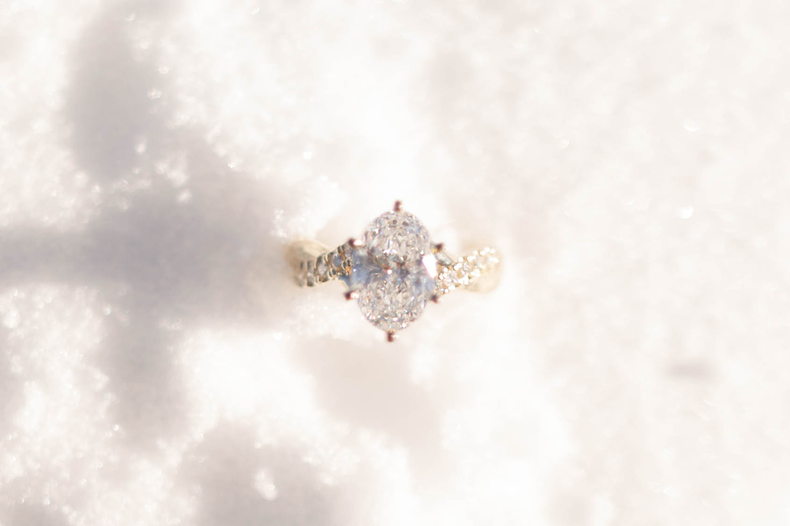 Sparkling engagement ring nestled in fresh white snow, surprise proposal ring close-up.