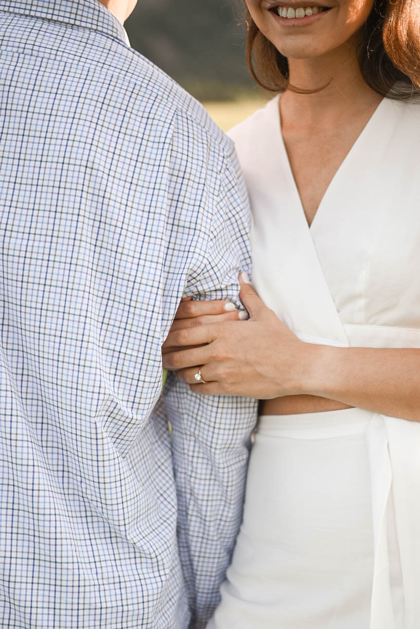 Bride-to-be resting her hand with engagement ring on her partner’s arm while standing together outdoors at Chautauqua Park, Boulder.