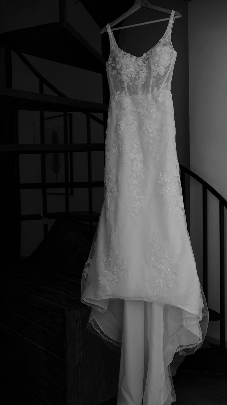 Bride’s wedding dress hanging on a wooden hanger inside the venue, showing lace details.