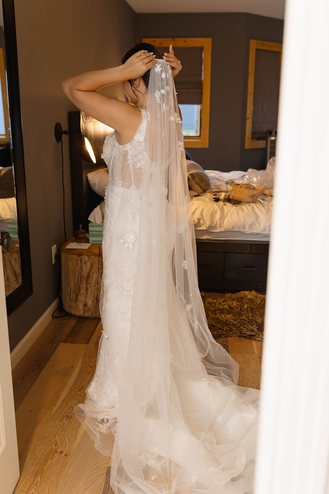 Bride adjusting her veil in a warmly lit room, preparing for her elopement day.