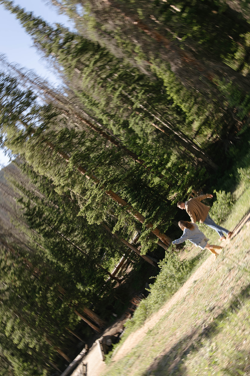 A motion-filled shot of a couple running hand in hand through the mountain forest, leaning into the fun of the moment.
