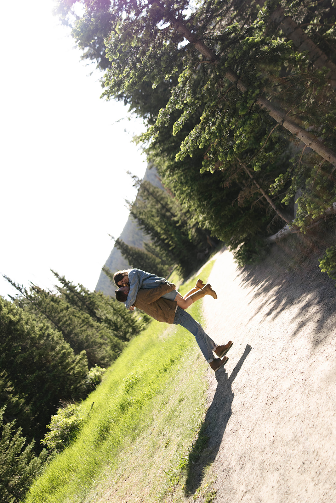 Groom lifts his partner playfully on a forest path, creating a candid and joyful mountain wedding–inspired shot.