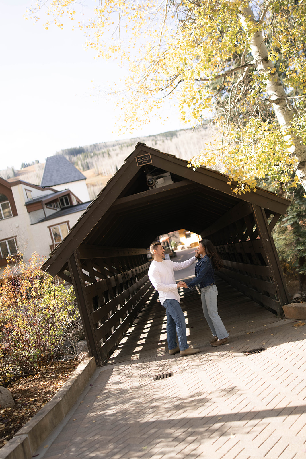 A couple dances together inside a covered wooden bridge, a charming spot in vail village in Colorado.