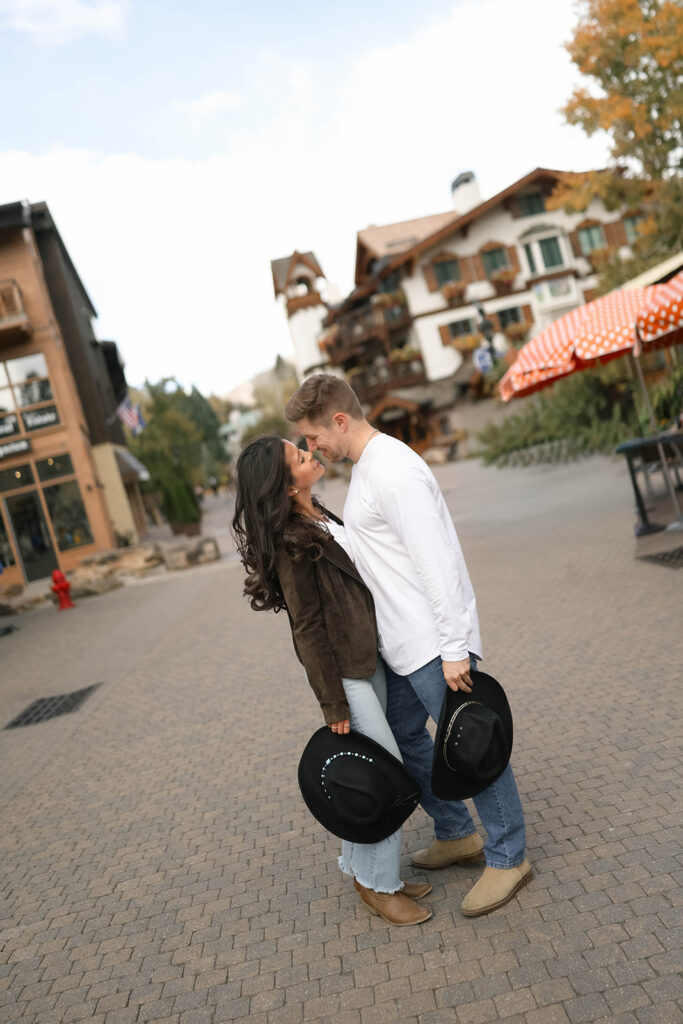 A couple walks side-by-side on a brick pathway, sharing a sweet glance in vail village in Colorado on an overcast day.