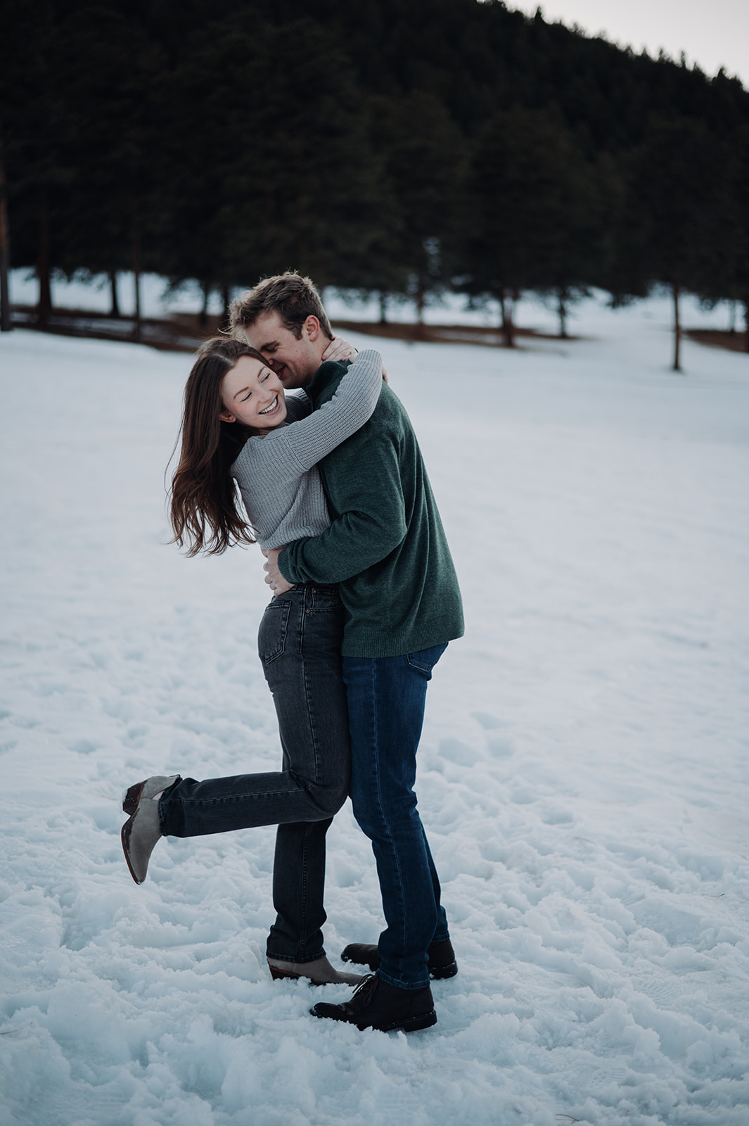 Wrapped in winter sweaters, the pair shares a joyful hug in the snow, a sweet, carefree couples photoshoot in the cold.