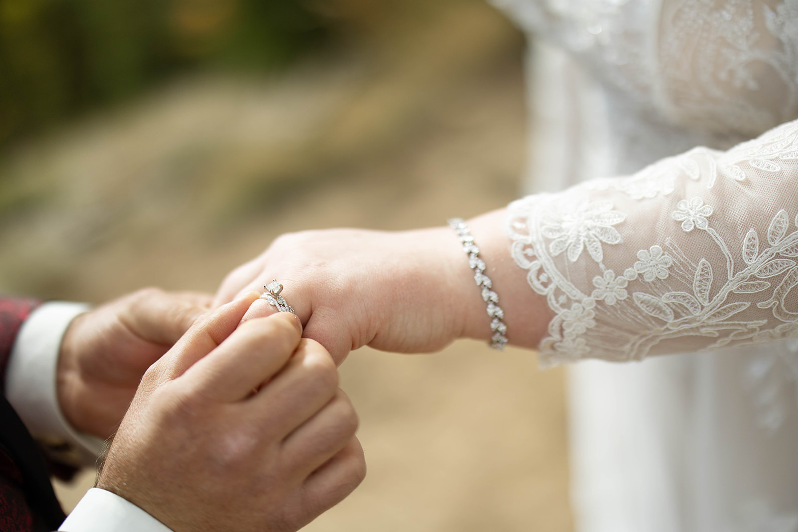 Close-up of a groom gently placing a ring on the bride’s finger, showcasing lace cuffs, jewelry, and the intimacy of the moment during an aspen elopement.