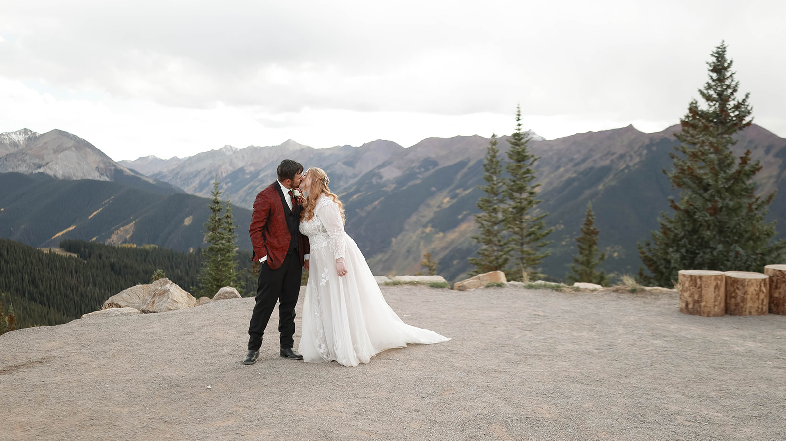 Couple sharing a kiss on a mountaintop during their aspen elopement, with dramatic peaks stretching across the horizon.