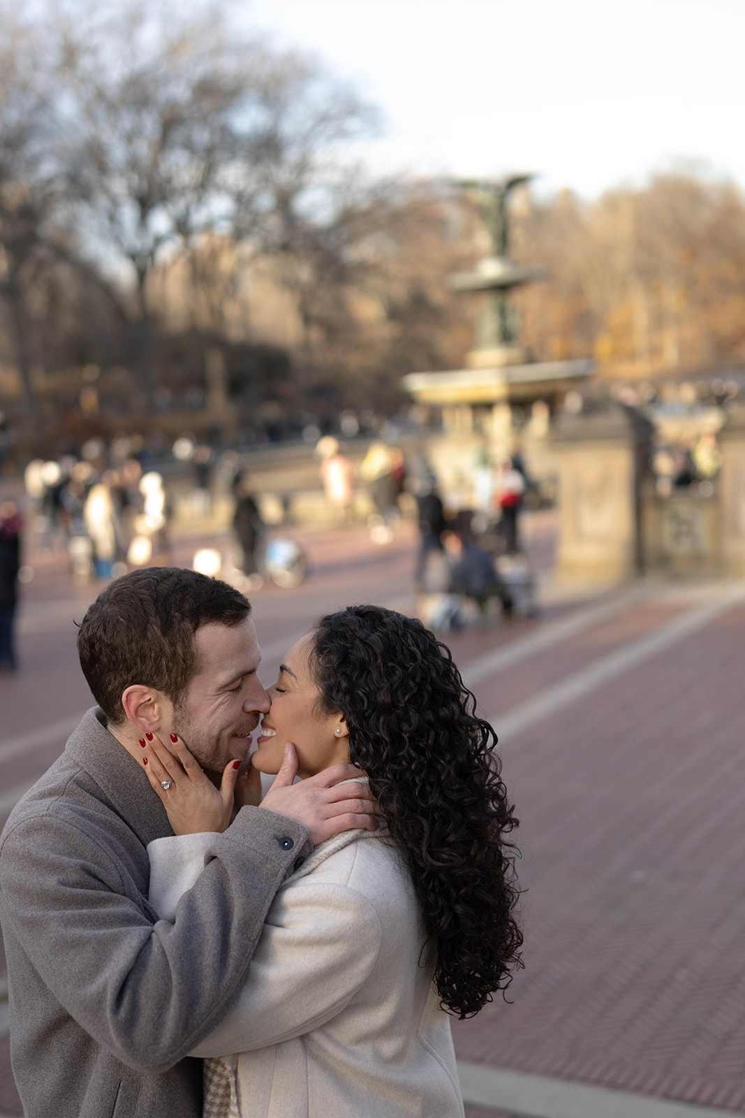 Close-up of the couple laughing and kissing near Bethesda Fountain, capturing candid emotion during their central park engagement photos.