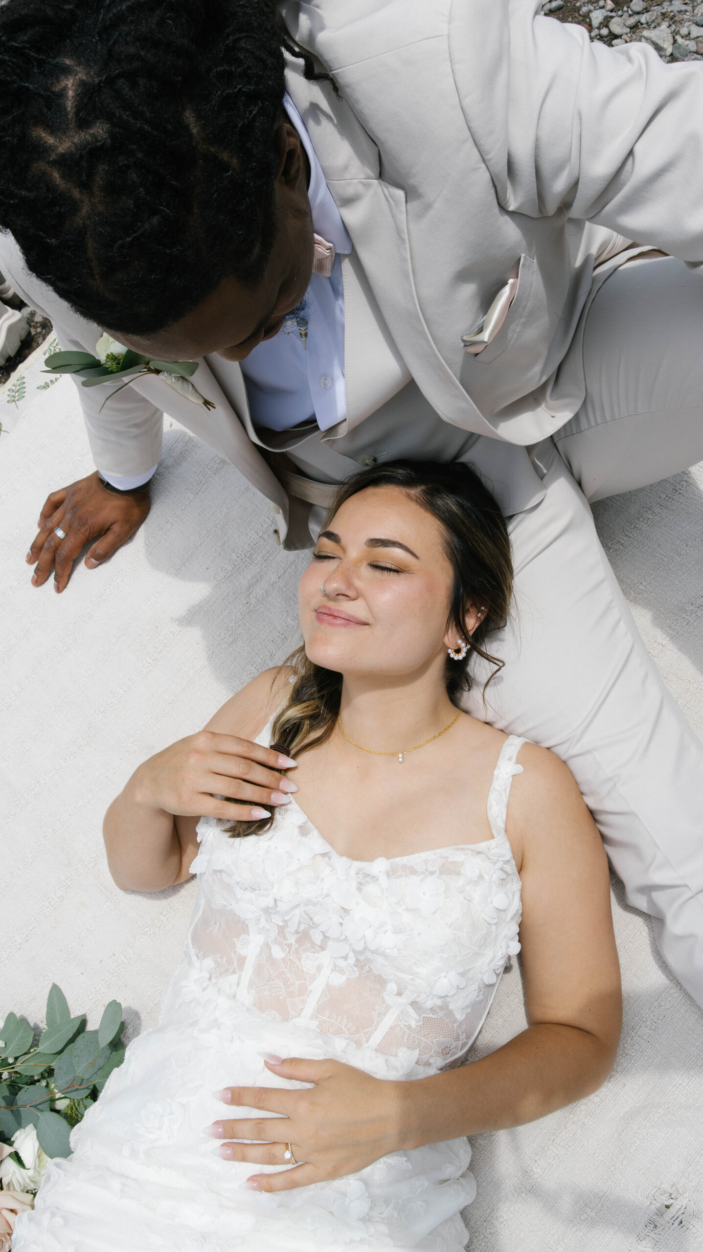 A peaceful moment of the bride lying with her head in the groom’s lap as they relax together outdoors, surrounded by soft textures and mountain air.