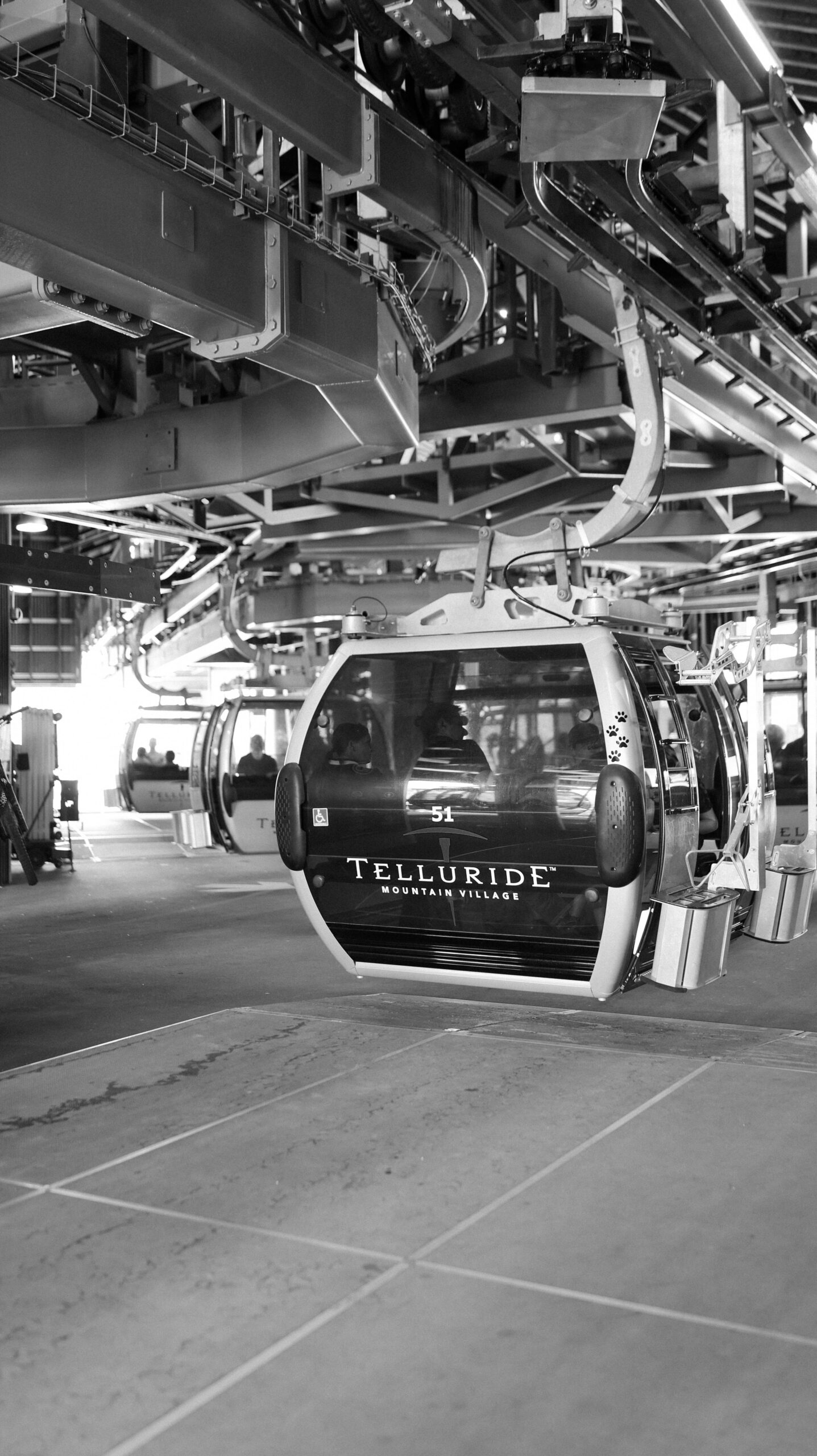 A black-and-white photo of the Telluride gondola station, showing several cabins lined up and ready for riders.