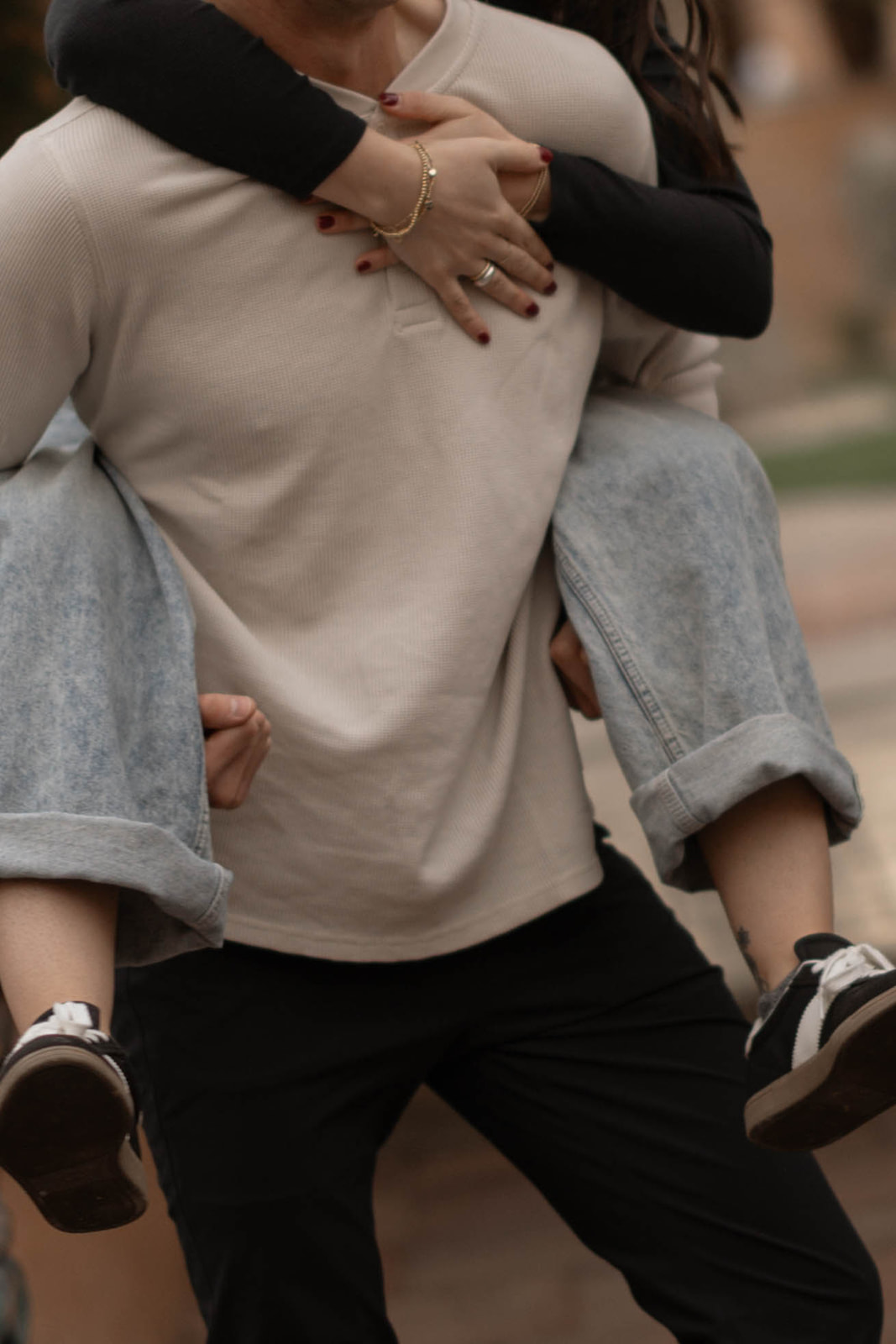 Close-up of a couple embracing as the man carries the woman piggyback, focusing on layered neutrals and denim textures that work well for casual couples outfit ideas.