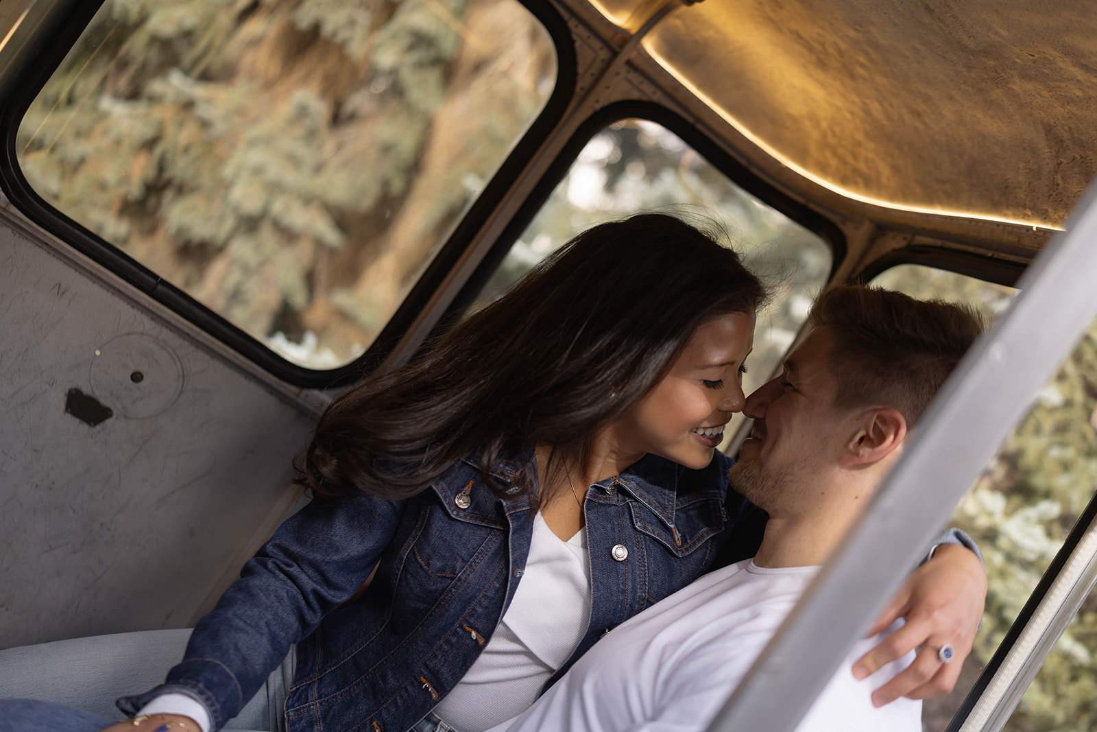 Couple cuddling inside a gondola cabin, smiling and leaning close during their vail village, colorado engagement session.