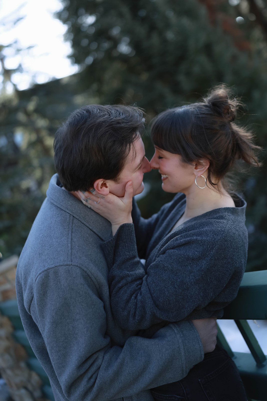 Couple holding hands and dancing beneath a covered wooden bridge during their fall engagement session in vail village, colorado.