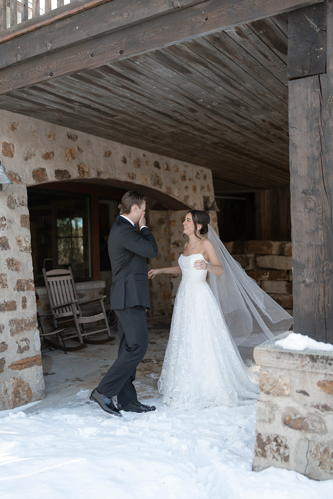 Bride and groom sharing an emotional laugh during their first look moment at a winter Breckenridge elopement, stone architecture framing the background.
