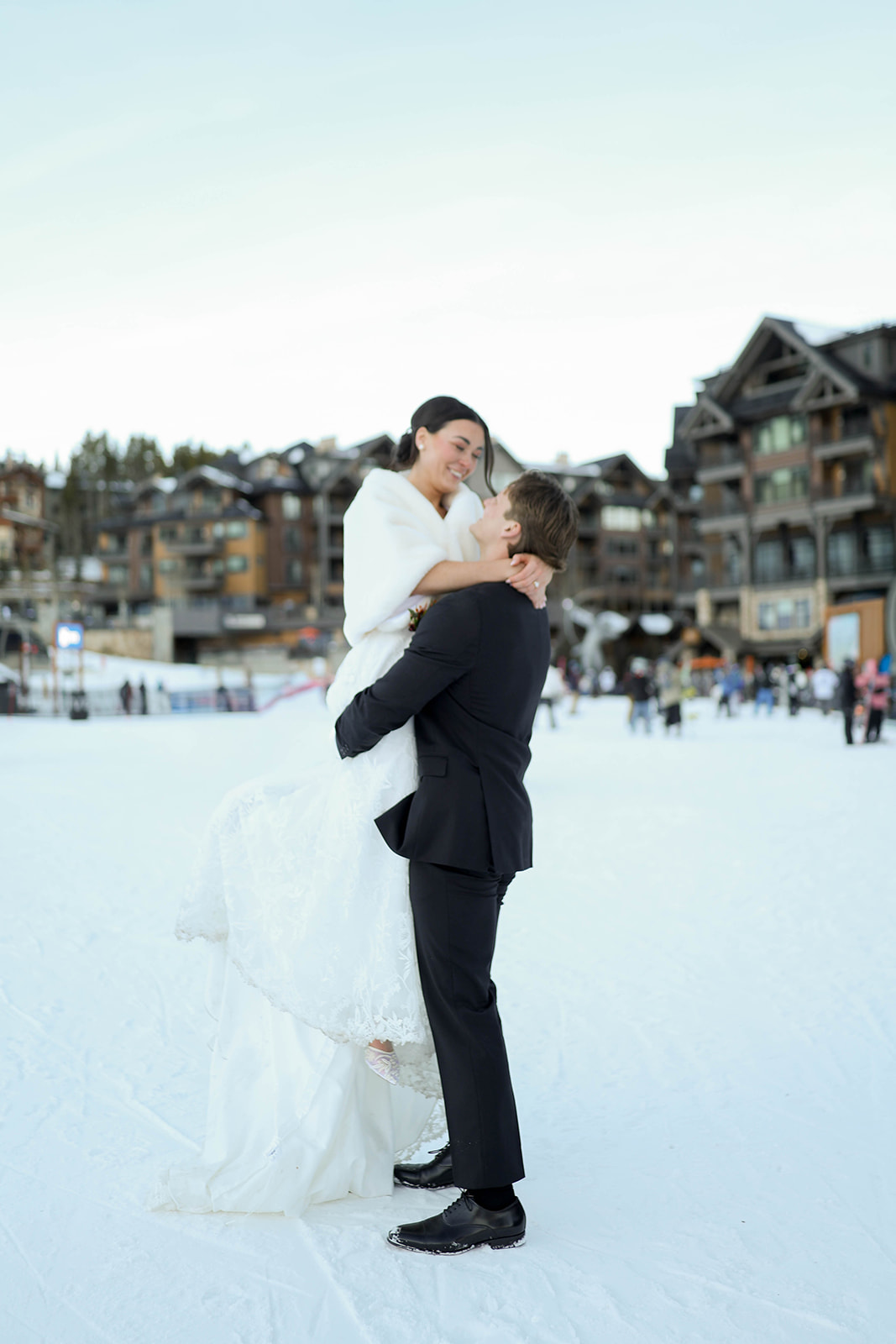 Groom lifting his bride in the snow during their Breckenridge elopement, surrounded by ski village buildings and winter scenery.