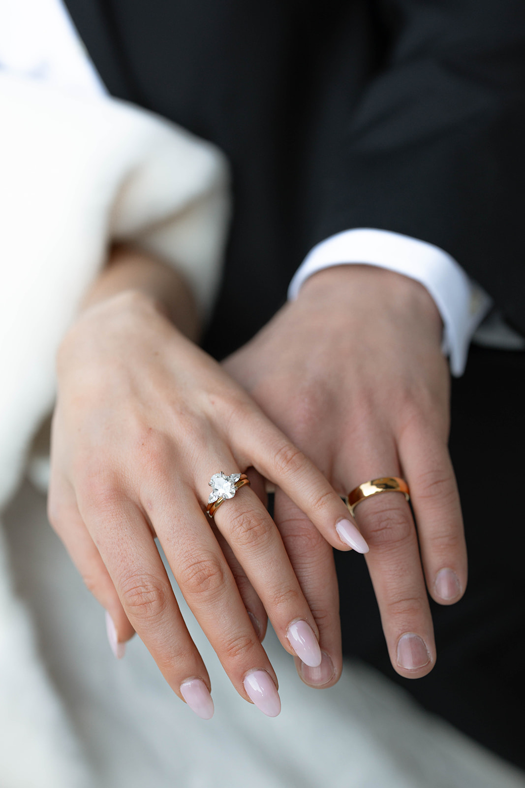 Close-up of couple’s hands showing an engagement ring with a large center stone and a gold wedding band, gently held together in a romantic detail shot from a Breckenridge elopement.