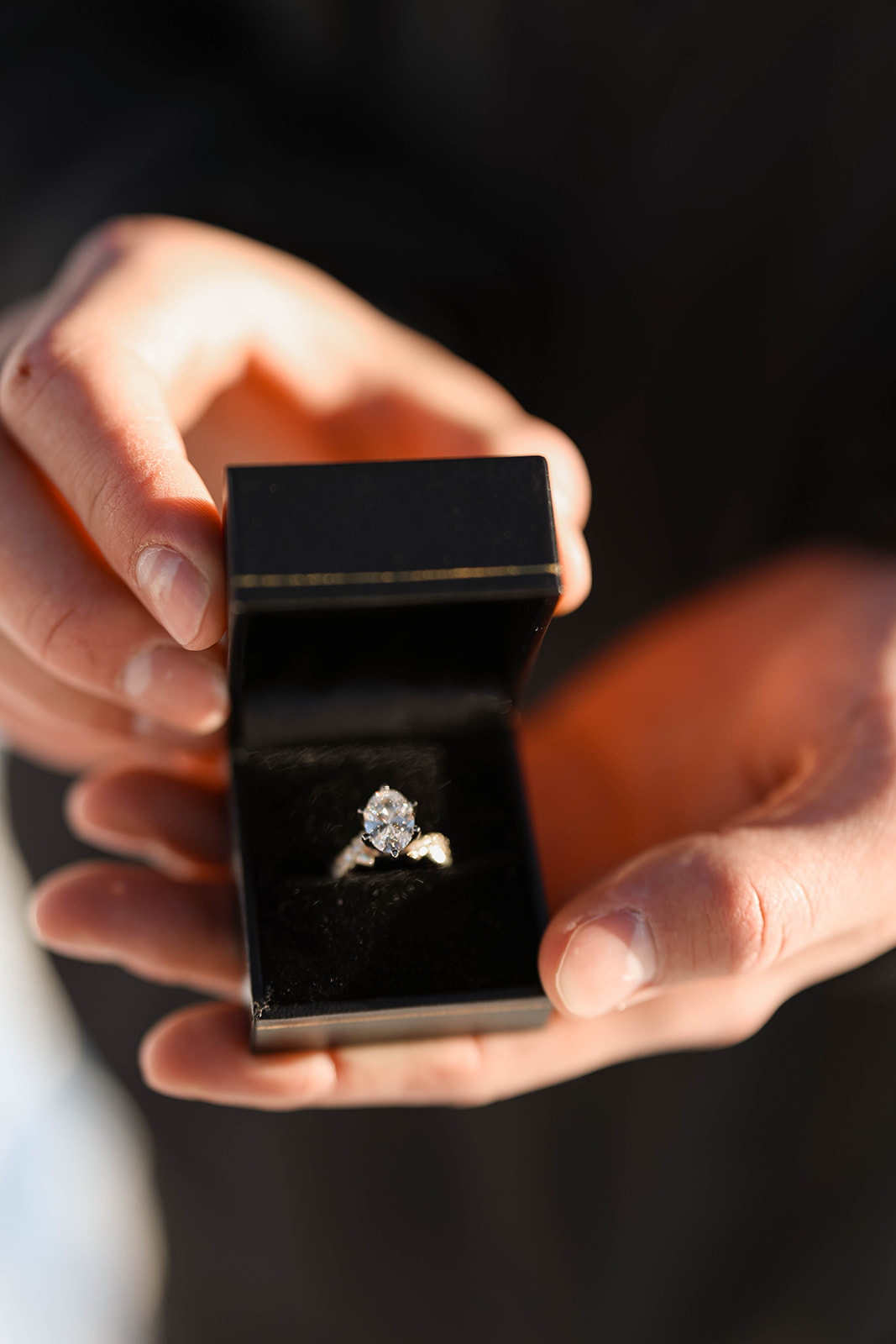 Close-up of an engagement ring displayed inside a black ring box during a mountain proposal.