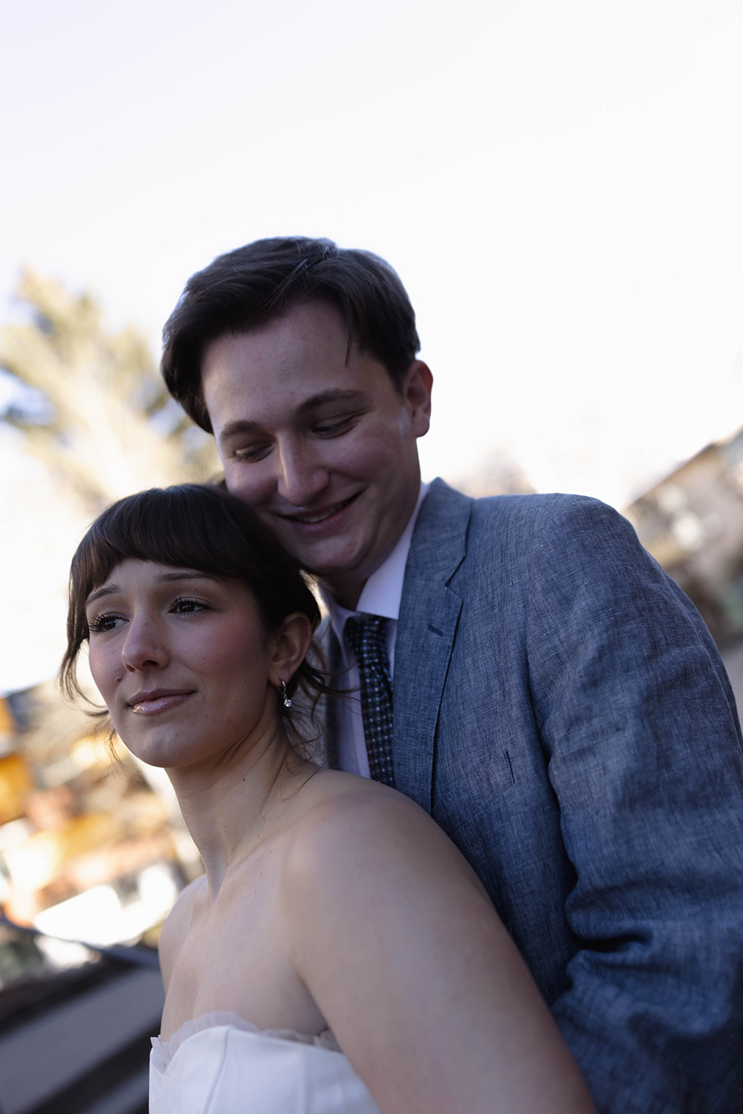 Close-up portrait of a bride and groom embracing, the groom smiling behind the bride as she looks off-camera during their intimate vail elopement.