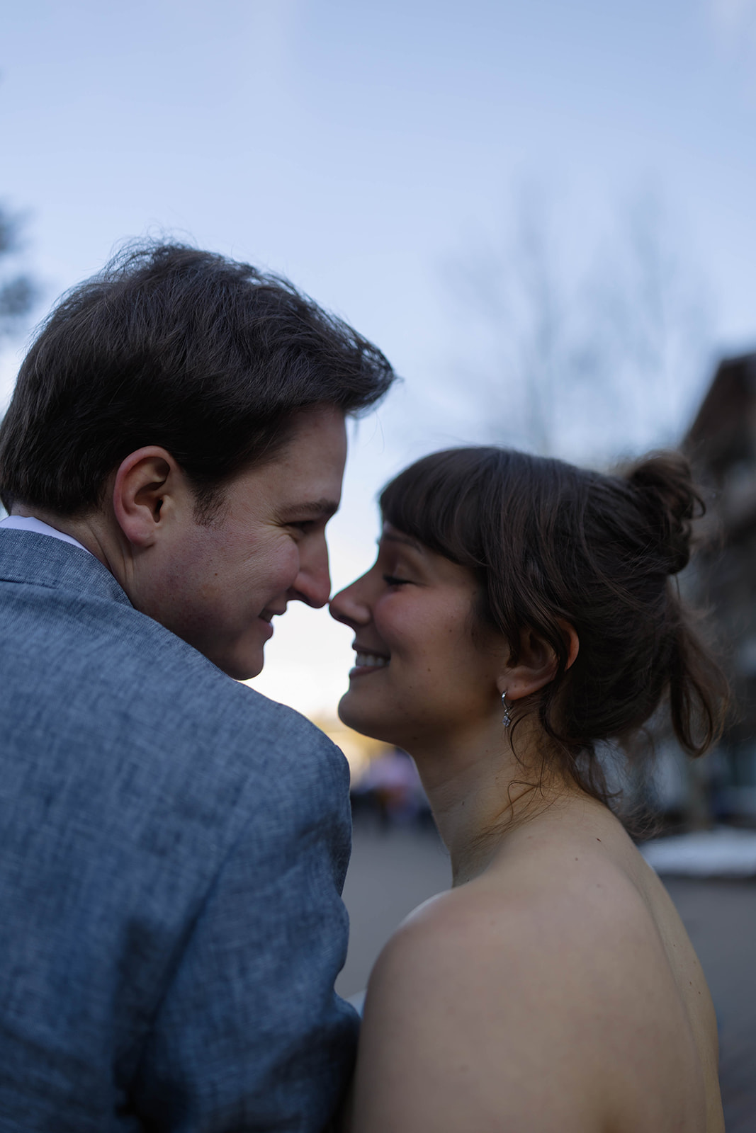 Couple leaning in close and smiling at each other during golden hour, captured in an intimate portrait with soft light and a cozy mountain-town backdrop during a Vail elopement.